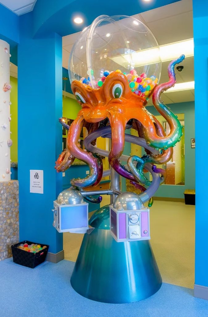 The octopus prize machine at CarlsbaDDS Pediatric Smiles, holding a bubble of prize capsules overhead