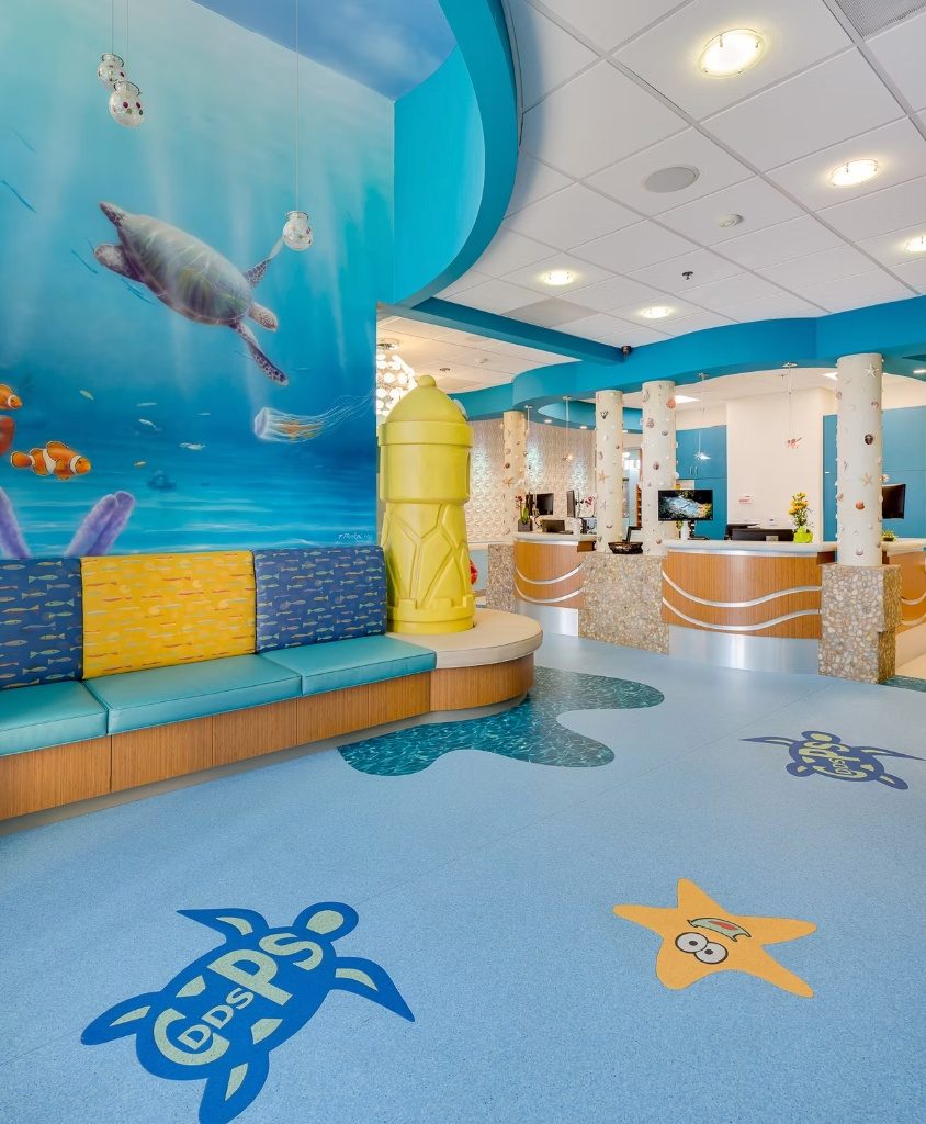 Ocean mural with sea turtles and clownfish above the waiting-room bench, the practice logo set into the floor