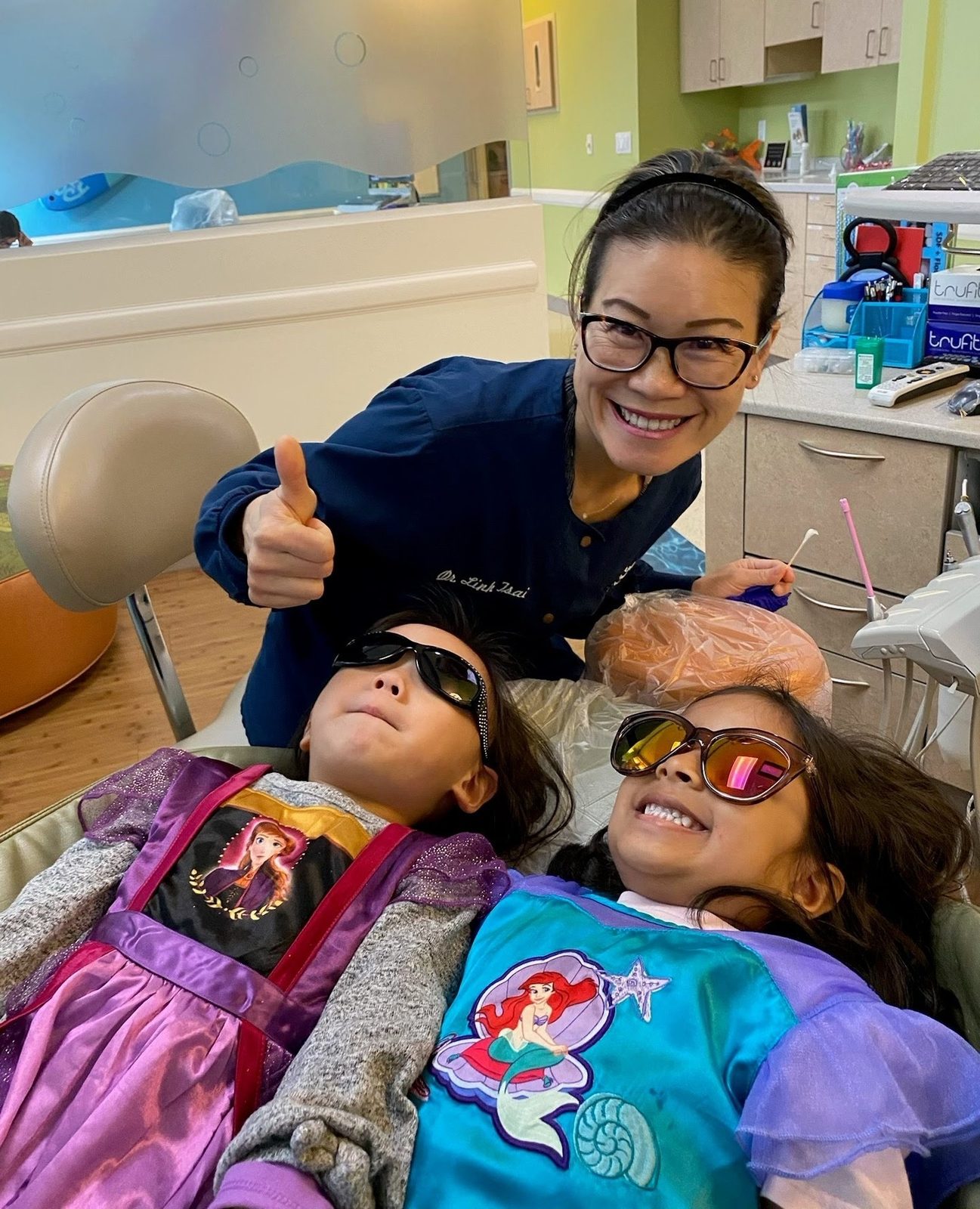 Dr. Linh Tsai with two young patients relaxing in the treatment chair