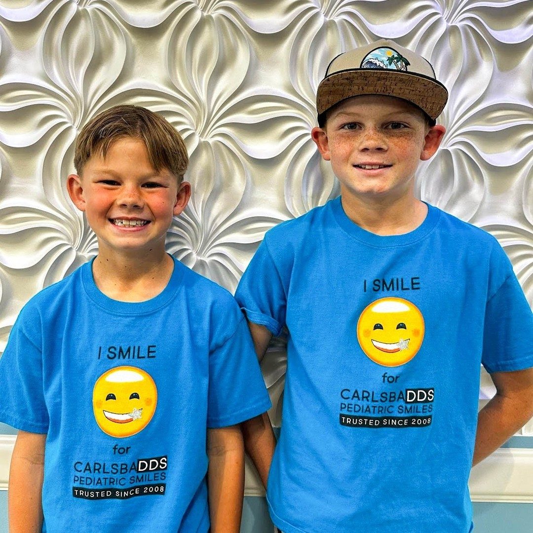 Two young patients wearing CarlsbaDDS Pediatric Smiles t-shirts