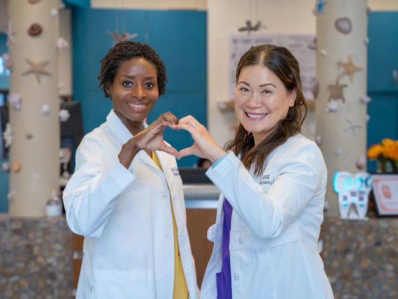 Dr. Judy Brown and Dr. Linh Tsai making a heart with their hands in the office lobby